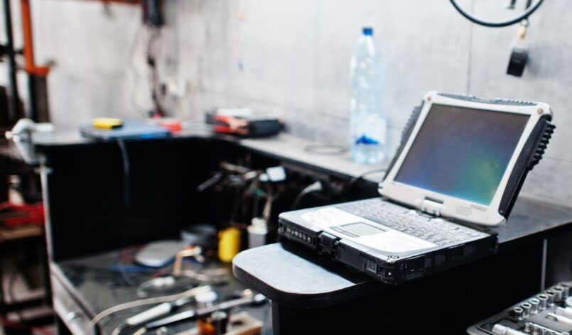 carkeys-autoschluessel-spezialist-reparatur Ein Werkstatttisch mit Diagnose-Laptop, Werkzeugen und elektronischem Equipment. Der Arbeitsplatz ist auf die Reparatur und Programmierung von Fahrzeugtechnik ausgerichtet und wirkt funktional und professionell.