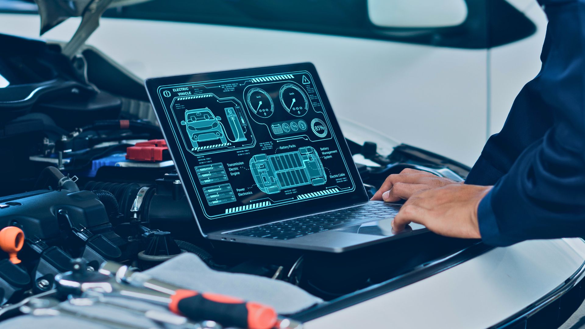 Ein Techniker steht vor einem geöffneten Motorraum und bedient ein Laptop mit digitaler Fahrzeugdiagnose-Software. Auf dem Bildschirm werden Systemdaten eines Elektrofahrzeugs angezeigt, darunter Akkustatus, Leistung und Antriebskomponenten.