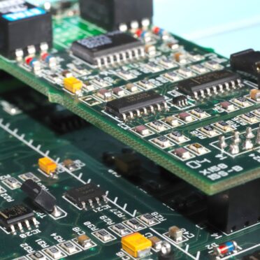 Nahaufnahme mehrerer übereinanderliegender grüner Leiterplatten mit integrierten Schaltkreisen, Kondensatoren und Widerständen – typisch für elektronische Steuergeräte im Fahrzeugbereich.